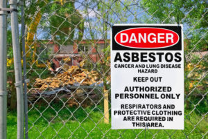 A sign on an outdoor fence reading warning people to keep out as asbestos is nearby