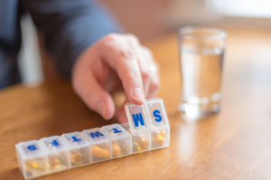 A person opens up a container of medications. 