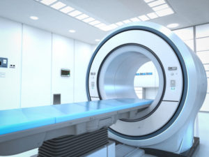 A radiation machine in a hospital. There's a flat table where the patient will lie and at its end is a circular radiation machine.