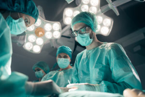 A group of doctors in blue medical outfits operate on a patient