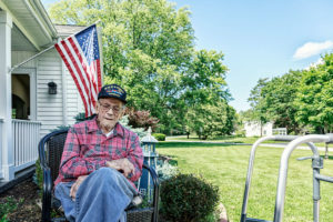 Veteran sits outside home in front of American flag