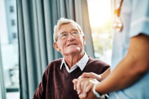 An older male patient looks up at a nurse