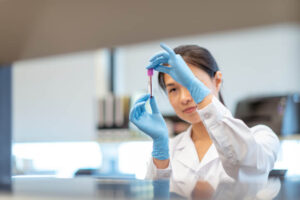 A female medical researcher holds up a small tube